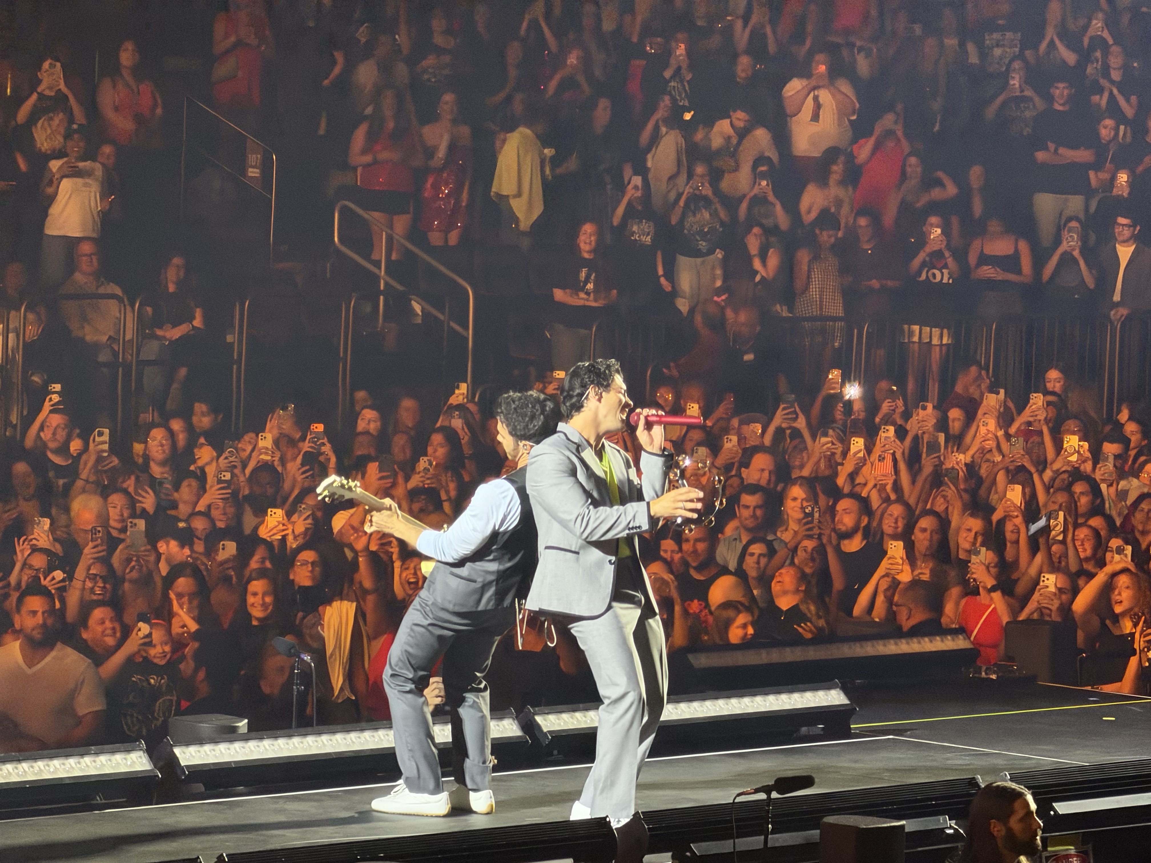 The Jonas Brothers performing together in front of the arena crowd.